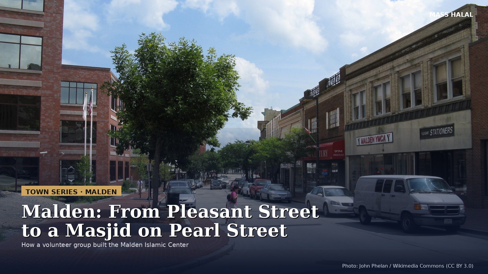 Pleasant Street in downtown Malden, Massachusetts, with brick storefronts, parked cars and a tree-lined brick sidewalk under a blue sky