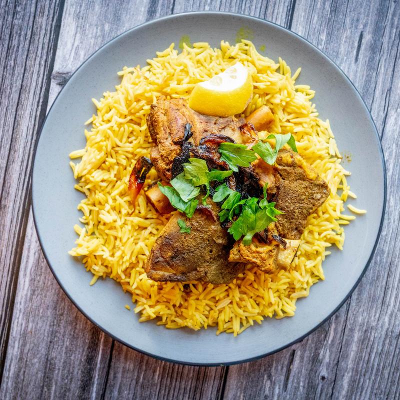 Bab Al-Yemen lamb haneeth over yellow basmati rice, garnished with parsley and lemon